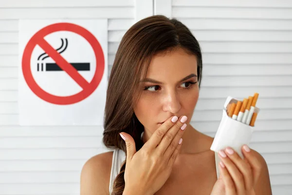Schöne Frau mit Zigarettenschachtel und Rauchverbotsschild — Stockfoto