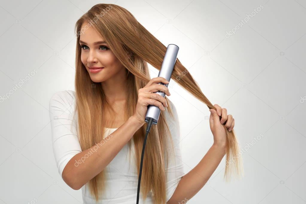 Straight Hair. Beautiful Woman Ironing Long Blonde Hair
