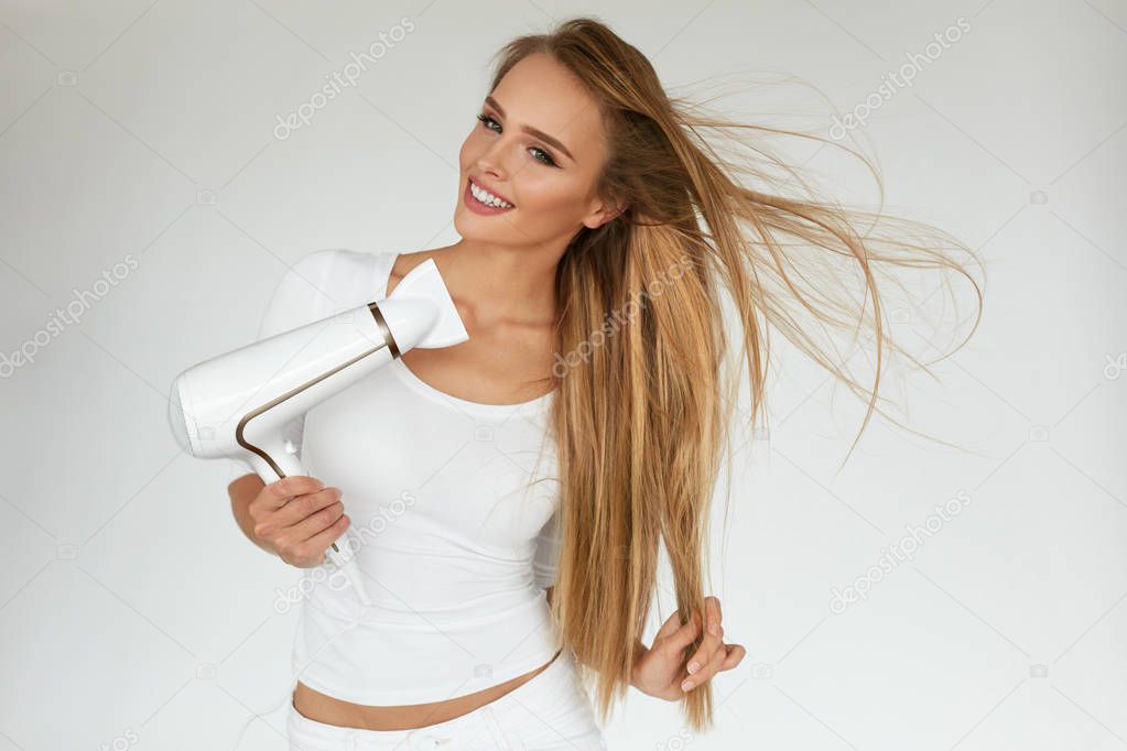 Hair Care. Woman Drying Beautiful Long Blonde Hair Using Dryer