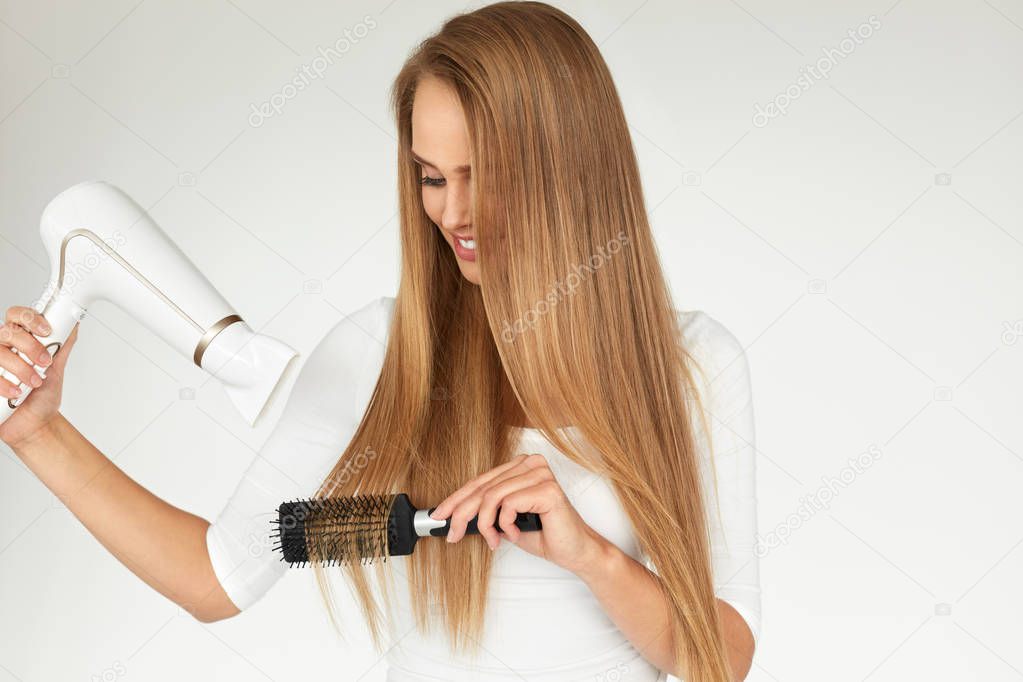 Hair Care. Woman Drying Beautiful Long Hair Using Dryer