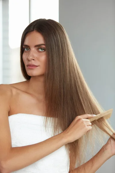 Расчесывание волос. Женщина расчесывает красивые длинные волосы расческой — стоковое фото