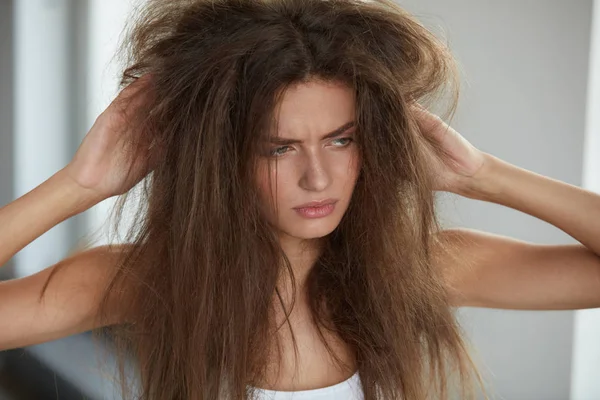 Mulher com segurando cabelos secos danificados por muito tempo. Danos no cabelo, Cuidados com os cabelos . — Fotografia de Stock