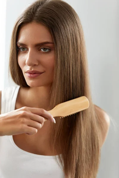 Kvinna som borstning vackra friska långa hår med borste porträtt — Stockfoto