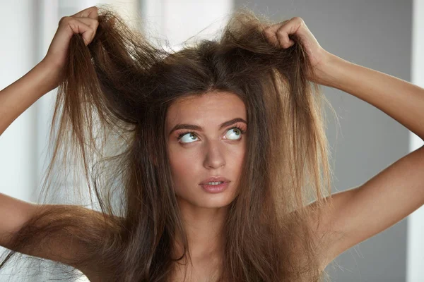 Жінка з проведення довгий пошкоджені сухого волосся. Пошкодження волосся, догляд за волоссям. — стокове фото