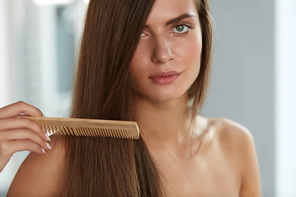 Расчесывание волос. Женщина расчесывает красивые длинные волосы расческой — стоковое фото