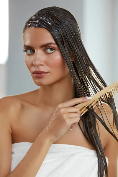 Hermosa mujer que pone la máscara en el pelo largo y húmedo. Cepillado — Foto de Stock