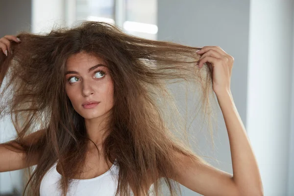 Mulher com segurando cabelos secos danificados por muito tempo. Danos no cabelo, Cuidados com os cabelos . — Fotografia de Stock