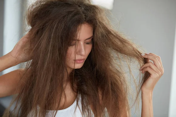 Mulher com segurando cabelos secos danificados por muito tempo. Danos no cabelo, Cuidados com os cabelos . — Fotografia de Stock