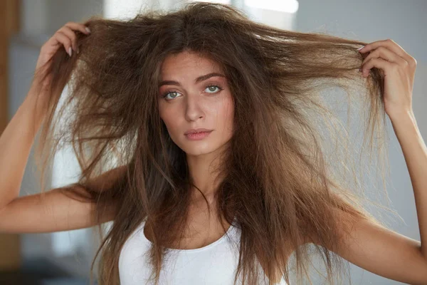 Mulher com segurando cabelos secos danificados por muito tempo. Danos no cabelo, Cuidados com os cabelos . — Fotografia de Stock