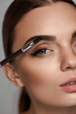Beautiful Woman Brushing Eyebrows With Brush. Beauty  clipart