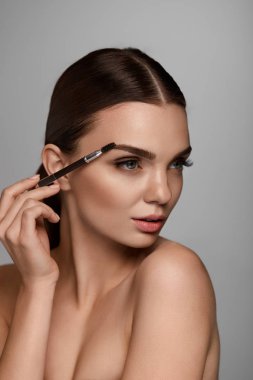 Beautiful Woman Brushing Eyebrows With Brow Tool clipart