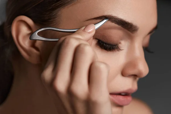 Frau mit geschlossenen Augen und Pinzette für Augenbrauen. Schönheitswerkzeuge — Stockfoto