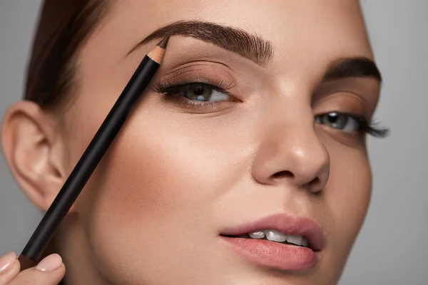 Schöne Frau, die Augenbrauen mit Bleistift konturiert. Schönheit — Stockfoto