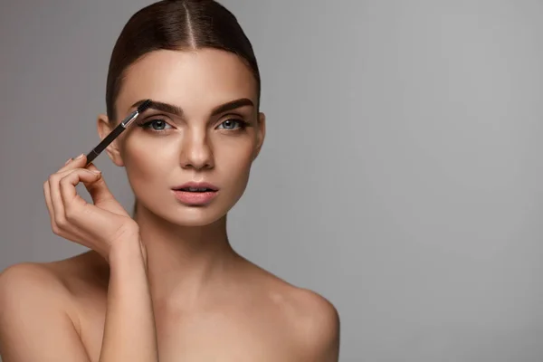 Hermosa mujer cepillando cejas con herramienta de la frente — Foto de Stock