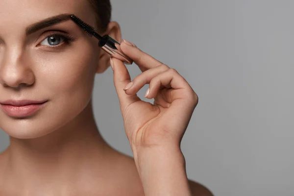 Hermosa mujer con maquillaje fresco y cepillo para las cejas — Foto de Stock