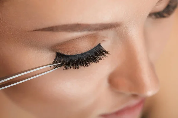 Beauty Make-up. Frau trägt schwarze falsche Wimpern mit Pinzette auf — Stockfoto