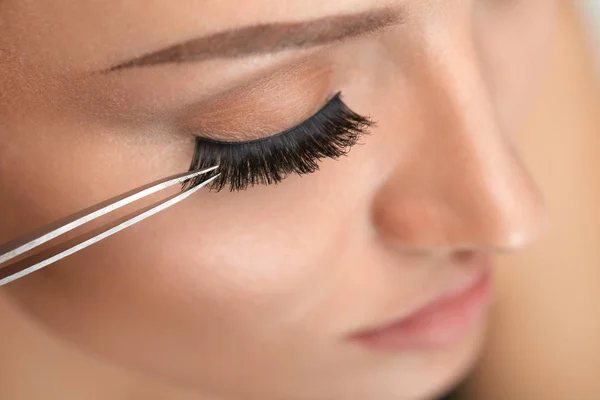 Maquillaje de belleza. Mujer aplicando pestañas falsas negras con pinza —  Fotos de Stock