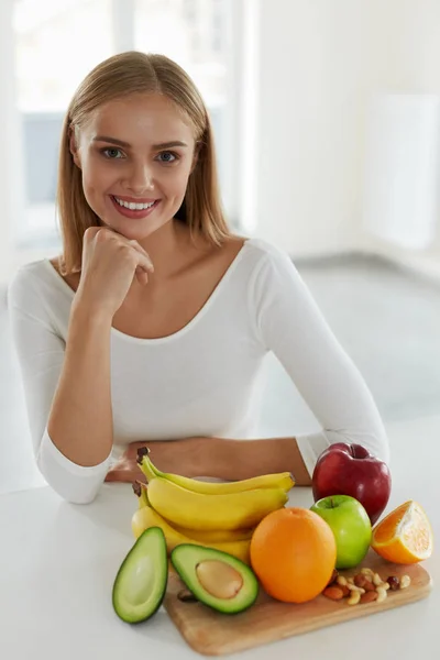 Beautiful Woman With Fruits And Nuts In Kitchen. Diet Nutrition
