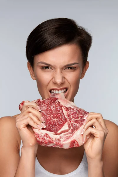 Eating Meat. Beautiful Woman Biting Raw Red Beef Meat With Teeth