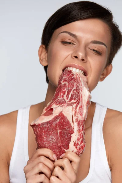 Eating Meat. Beautiful Woman Biting Raw Red Beef Meat With Teeth