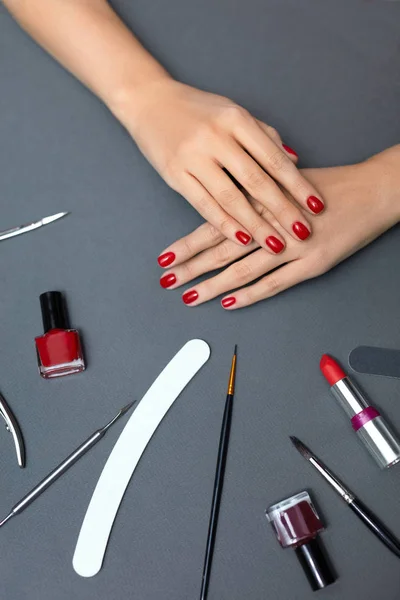 Belleza. Hermosas uñas femeninas con esmalte de uñas rojo y herramientas —  Fotos de Stock