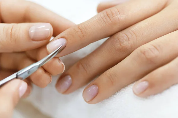 Manicure. Hands Removing Cuticle From Woman Hand With Scissors