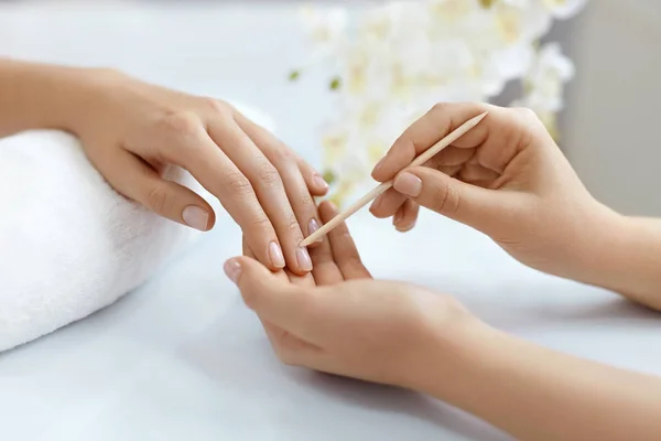 Primeros planos de las manos empujando la cutícula en las uñas femeninas con palo de madera —  Fotos de Stock