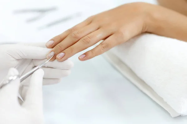 Cuidado de las uñas. Las manos femeninas cortan cutículas con tijeras. Manicura — Foto de Stock