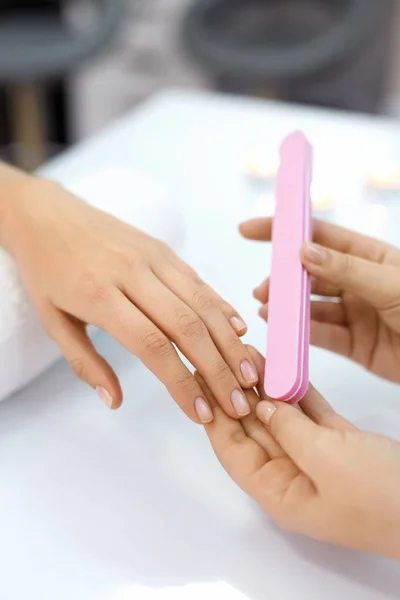 Manicura. Las manos femeninas puliendo uñas con lima de uñas en el salón — Foto de Stock