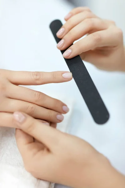 Manicura. Primeros planos de las manos femeninas de la limadura de uñas con la herramienta de cuidado de uñas —  Fotos de Stock