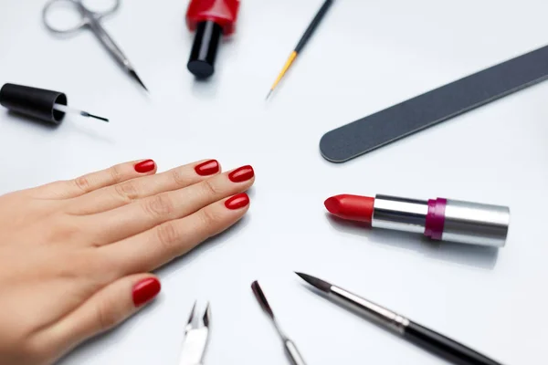 Manicura. Hermosa mano de mujer con esmalte de uñas rojo y herramientas — Foto de Stock