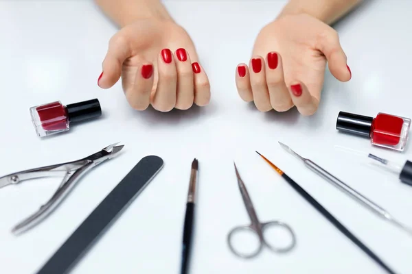 Cuidado de las uñas. Manos de mujer con esmalte de uñas rojo y herramientas de manicura —  Fotos de Stock