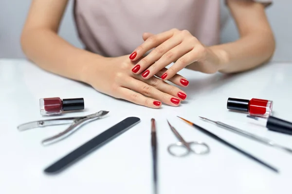 Cuidado de las uñas. Manos de mujer con esmalte de uñas rojo y herramientas de manicura —  Fotos de Stock