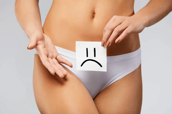 Salud de la mujer. Cuerpo femenino sosteniendo triste tarjeta sonriente cerca del estómago — Foto de Stock