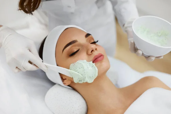 Cuidados com a pele facial. Mulher bonita recebendo máscara cosmética no salão — Fotografia de Stock