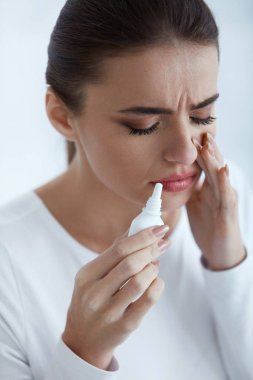 Soğuk. Güzel kadın burun spreyi kullanarak