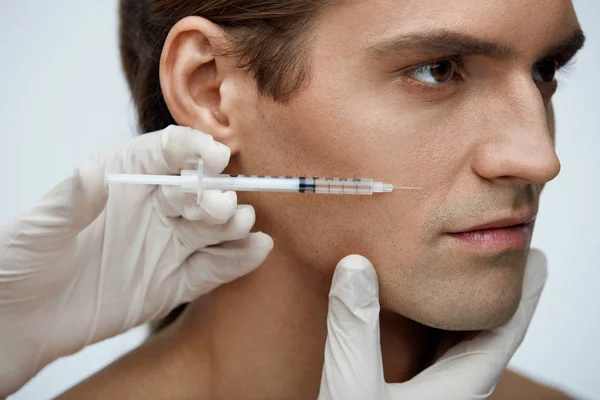 Cosmetología. Hombre guapo recibiendo inyecciones de relleno en la piel de la cara — Foto de Stock