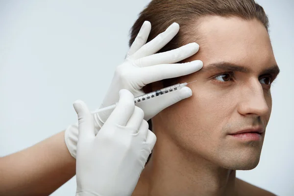 Cosmetologia. Homem bonito recebendo injeções de enchimento na pele do rosto — Fotografia de Stock