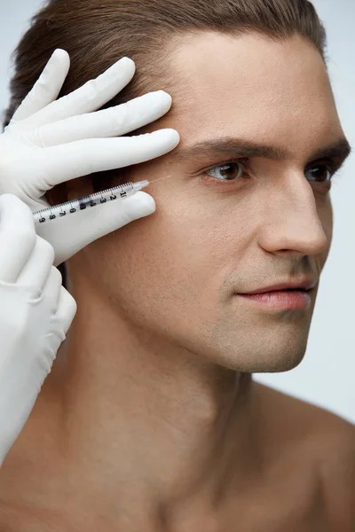 Cosmetología. Hombre guapo recibiendo inyecciones de relleno en la piel de la cara —  Fotos de Stock