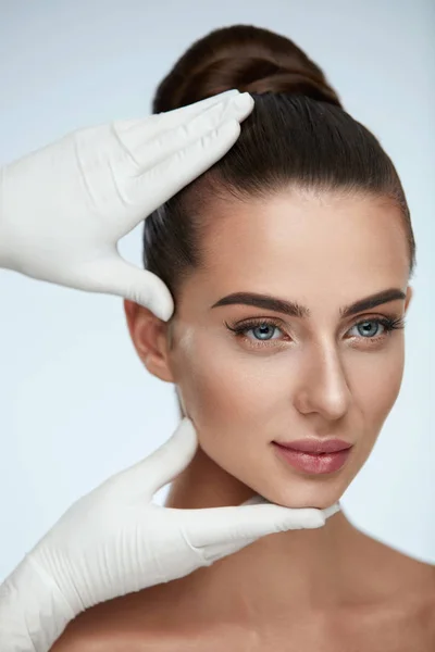 Belleza facial. Las manos en los guantes tocando la cara de la mujer — Foto de Stock