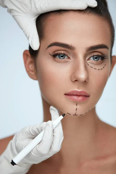 Behandeling. Schoonheidsspecialiste tekenen chirurgische lijnen op vrouw gezicht — Stockfoto