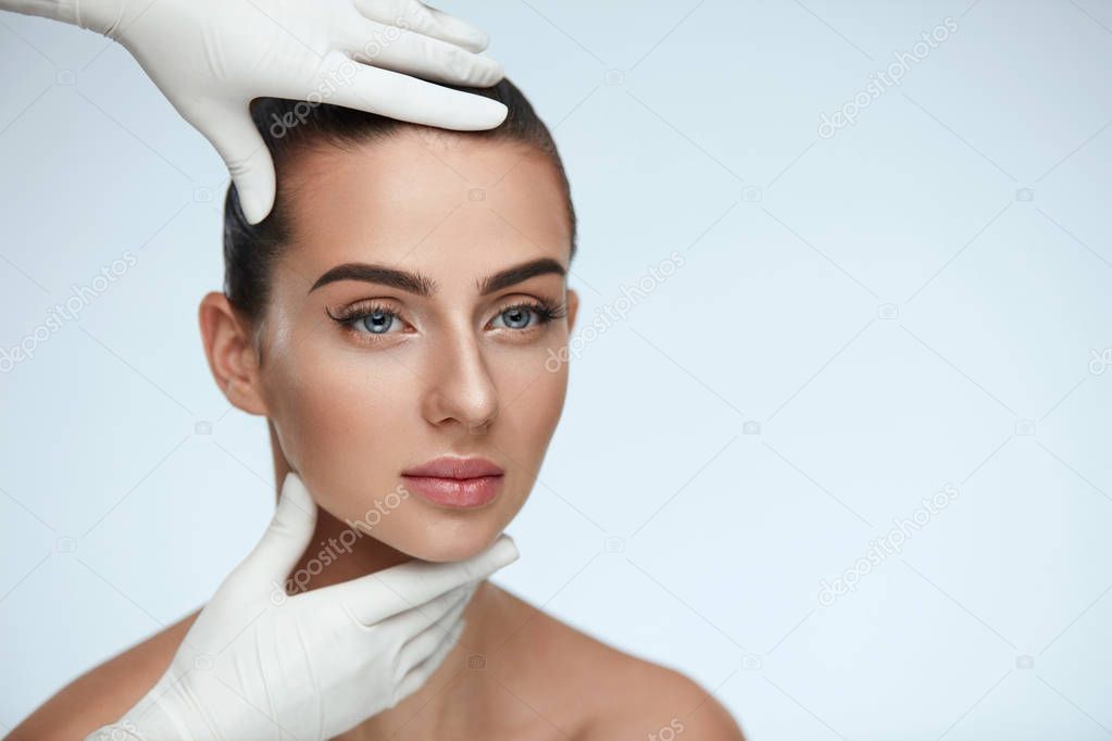 Facial Beauty. Hands In Gloves Touching Woman's Face