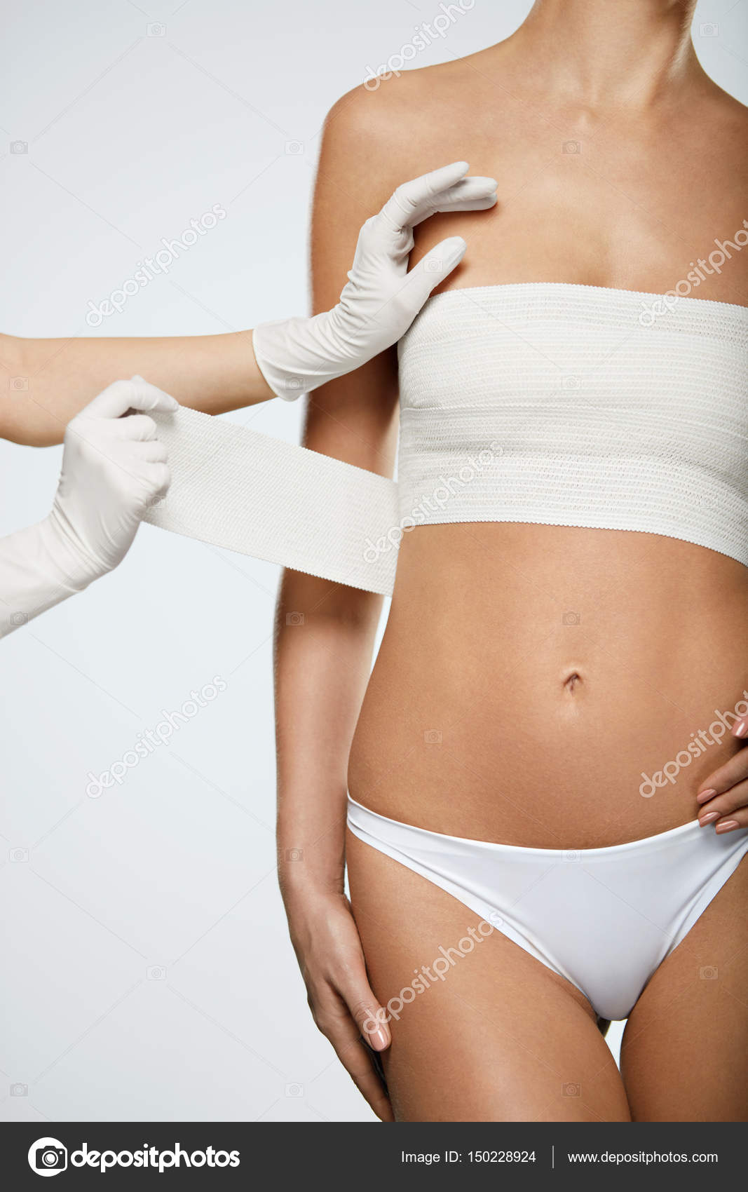 Plastic Surgery. Doctor Hands Wrapping Female Breast In Bandage Stock