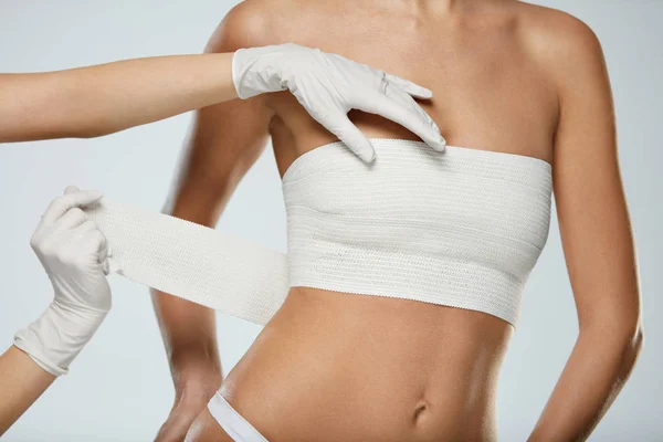 Plastische Chirurgie. Ärztin wickelt weibliche Brust in Verband — Stockfoto