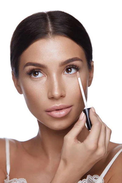 Hermosa mujer aplicando corrector en la cara de belleza. Maquillaje — Foto de Stock