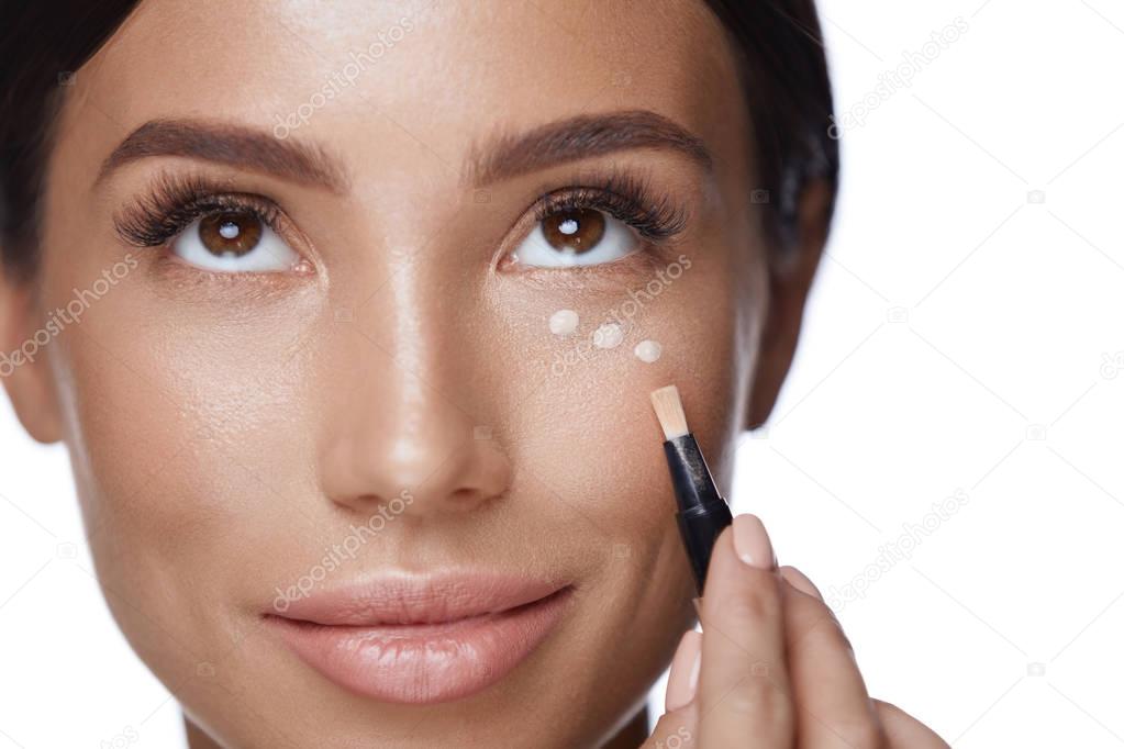Cosmetics. Beautiful Woman Applying Concealer On Skin Under Eyes
