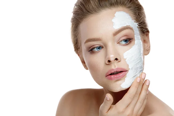 Cura della pelle. Giovane donna che applica maschera bianca sul viso. Cosmetici — Foto Stock