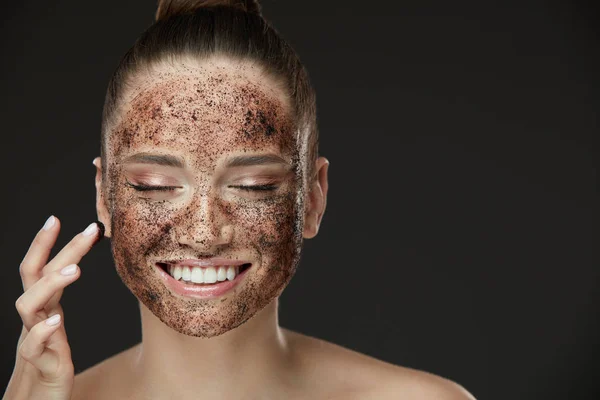 脸部皮肤磨砂膏。微笑女孩咖啡面膜磨砂膏在皮肤中的应用 — 图库照片