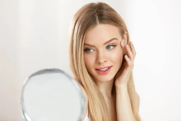 Cuidado facial de belleza. Chica con la piel sana mirando en el espejo — Foto de Stock
