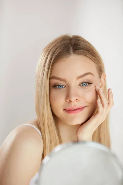 Cuidado facial de belleza. Chica con la piel sana mirando en el espejo —  Fotos de Stock